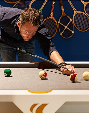Joueur réalisant un coup sur un billard Cornilleau avec des boules de billard en gros plan.
