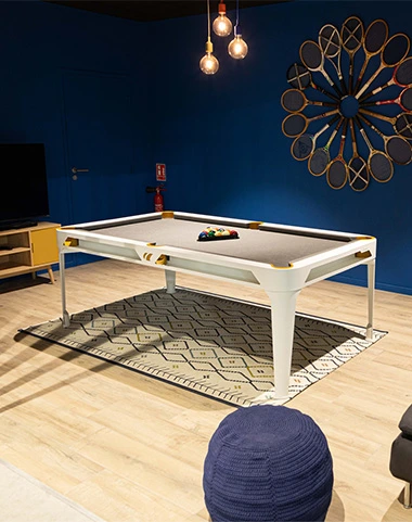 Billard Hyphen Cornilleau blanc installé dans une pièce moderne avec mur bleu et décoration murale.