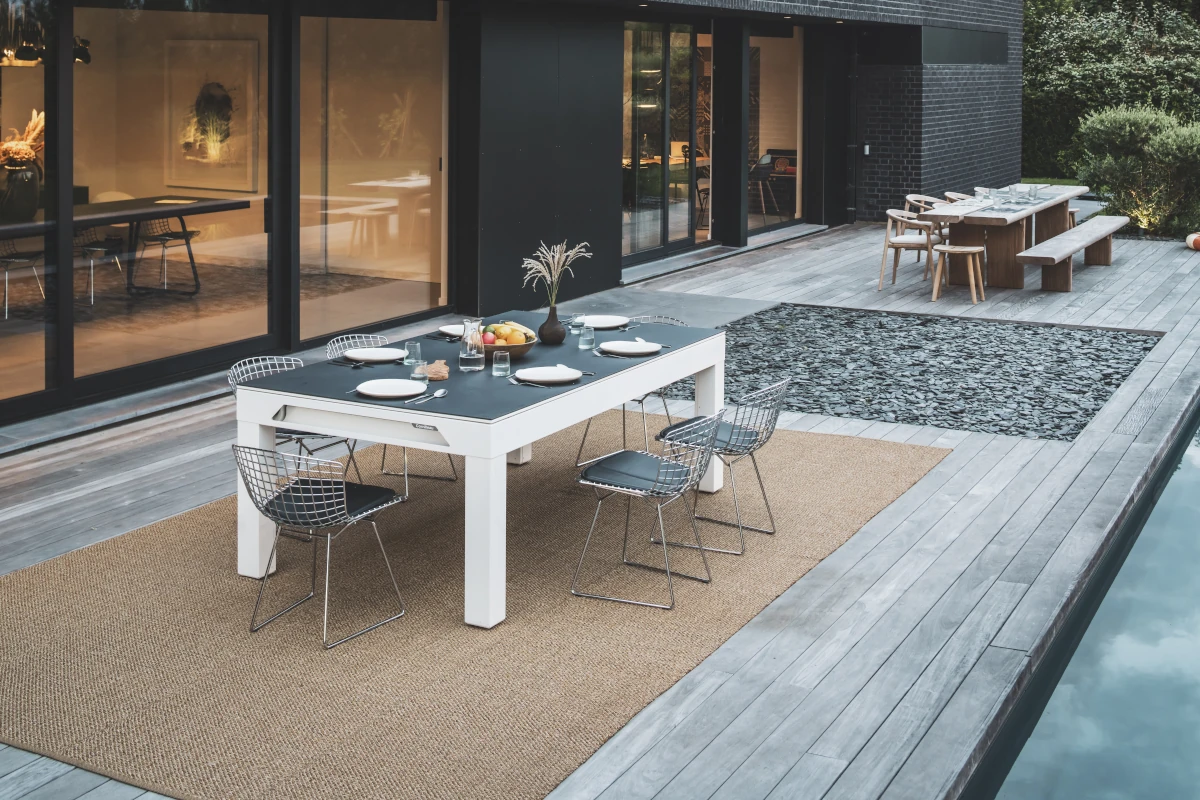 Table Cornilleau convertible en table à manger sur une terrasse moderne avec piscine.