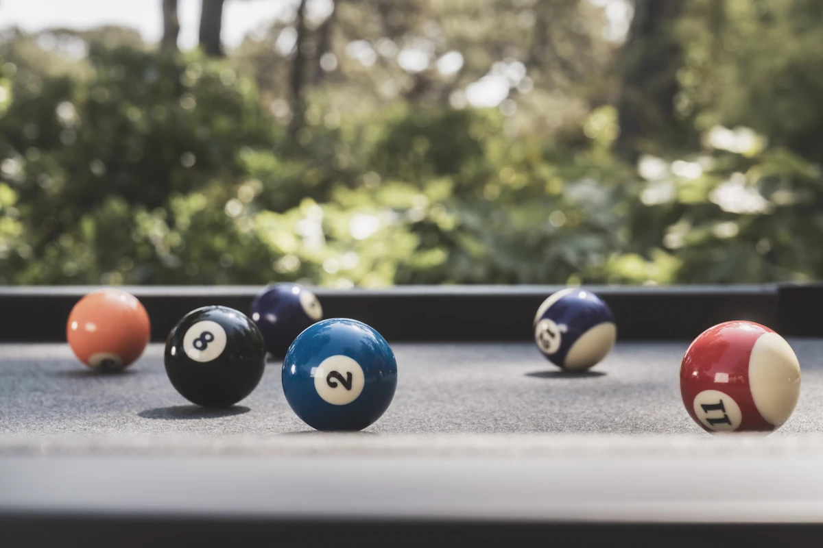 Boules de billard sur un tapis gris avec jardin en arrière-plan