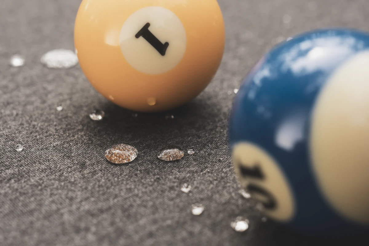 Gros plan sur des boules de billard et des gouttes de soda sur le tapis gris.