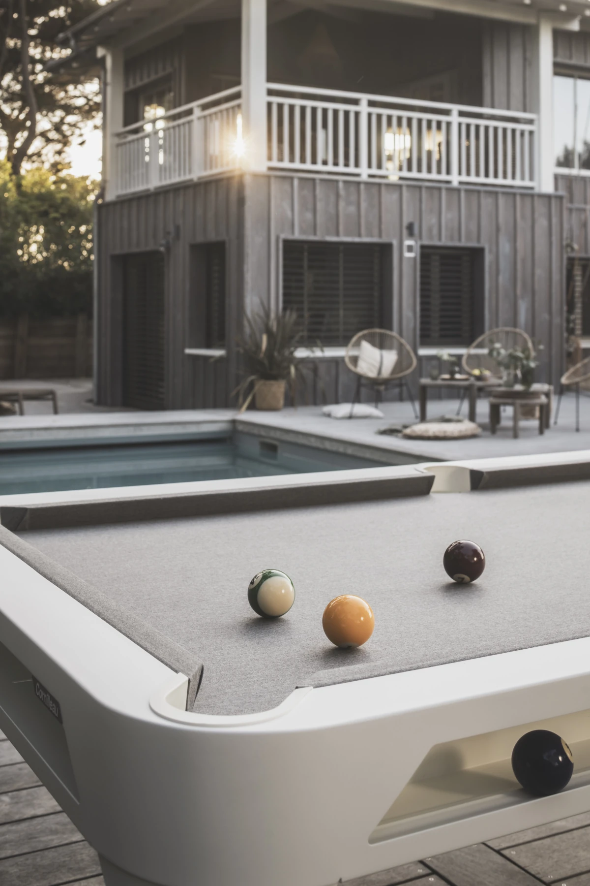 Billard Cornilleau blanc installé en extérieur près d’une piscine et d’une maison avec terrasse.