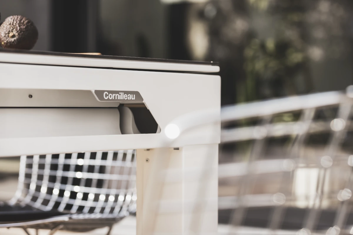Détail du logo Cornilleau sur une table design blanche en extérieur.