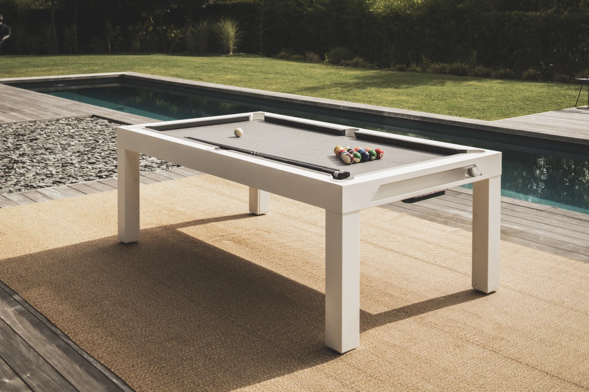 Table de billard d'extérieur blanche Cornilleau installée sur une terrasse avec piscine