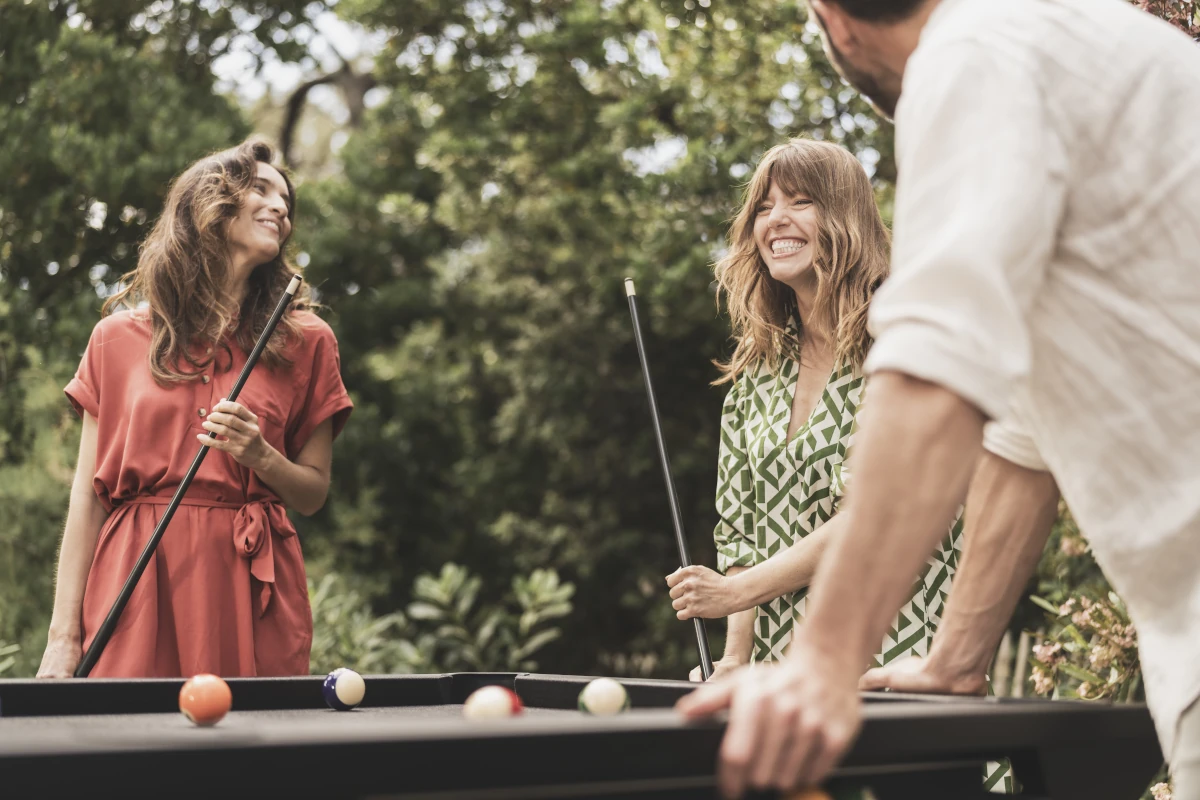 Amis jouant au billard en extérieur autour d'un billard design Cornilleau.