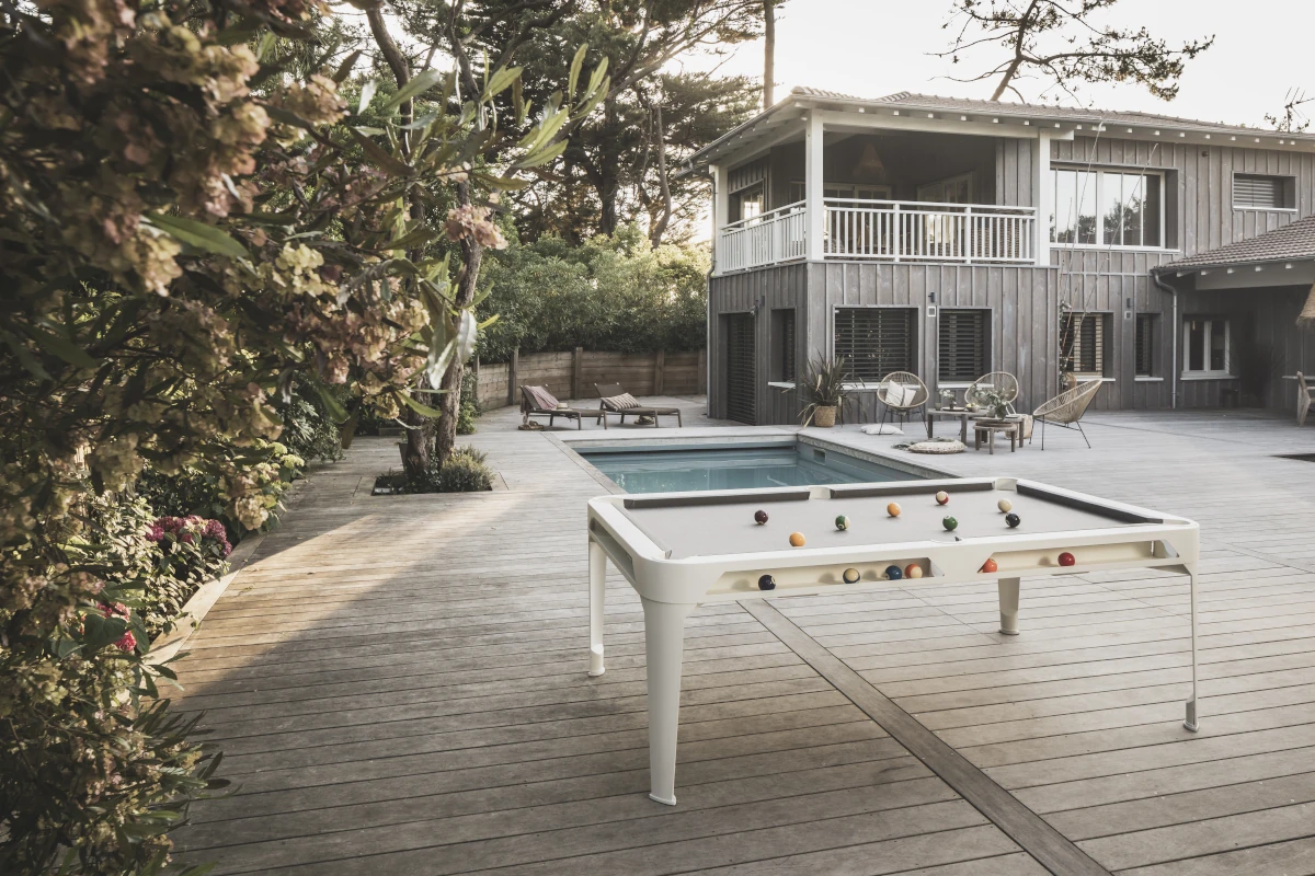 Billard d'extérieur Cornilleau installé sur une terrasse avec piscine et jardin