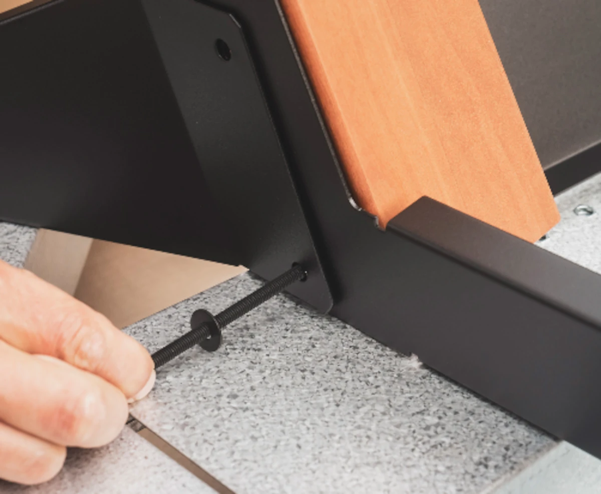 **Alt image :** Fixation d’un pied en bois sur la structure métallique noire d’un billard Cornilleau lors du montage.