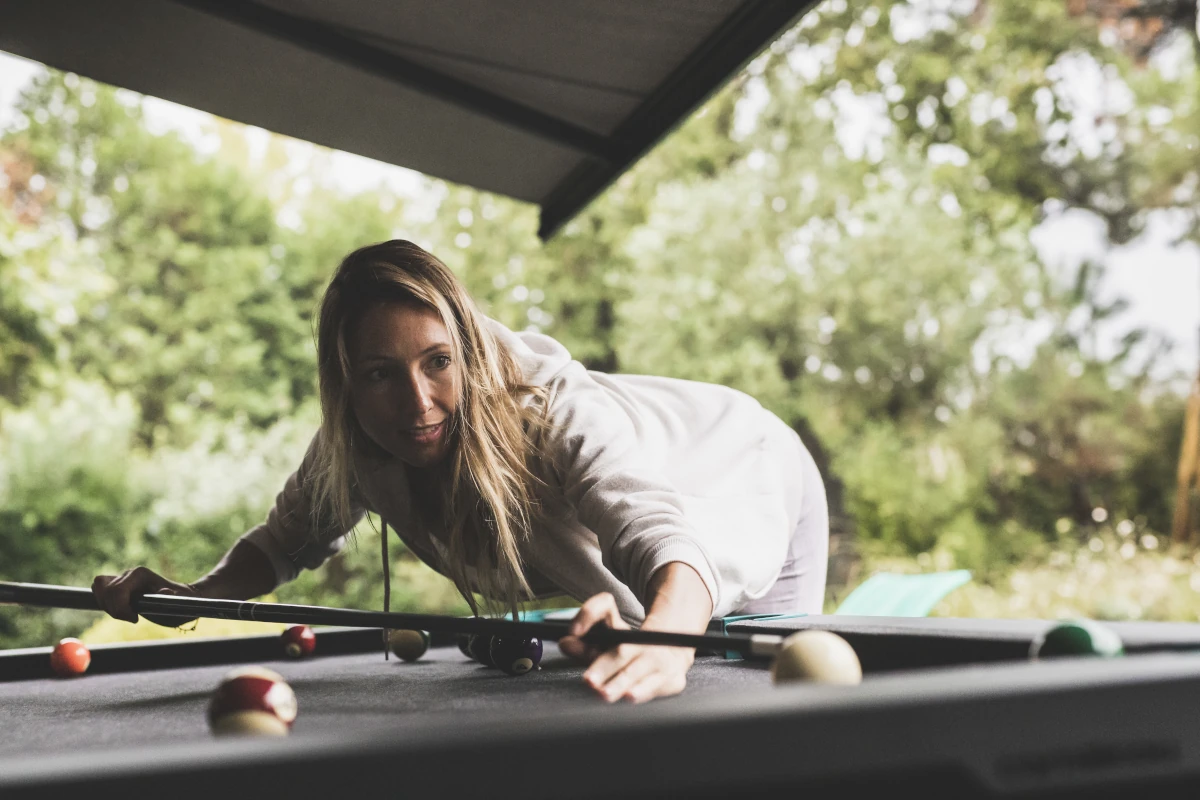 Les billards convertibles : multipliez l’utilisation de vos espaces ! Les trois collections de billards Cornilleau sont convertibles grâce à des plateaux de conversion qui transforment le billard en table. Pour un projet d’agencement professionnel, c’est un avantage immense : la surface n’est plus mono-usage. Imaginez une salle de séminaire qui accueille une table de travail le jour et un billard le soir, un lobby qui dispose d’une table de buffet pour un cocktail ou encore une terrasse d’hôtel qui gagne une grande table de repas. Pour la même surface, chaque mètre carré porte deux fonctions. C’est l’argument le plus souvent décisif auprès d’un maître d’ouvrage qui arbitre des modèles d’exploitation. Les plateaux se rangent dans un espace dédié sous la table, ce qui évite de prévoir un local de stockage supplémentaire.