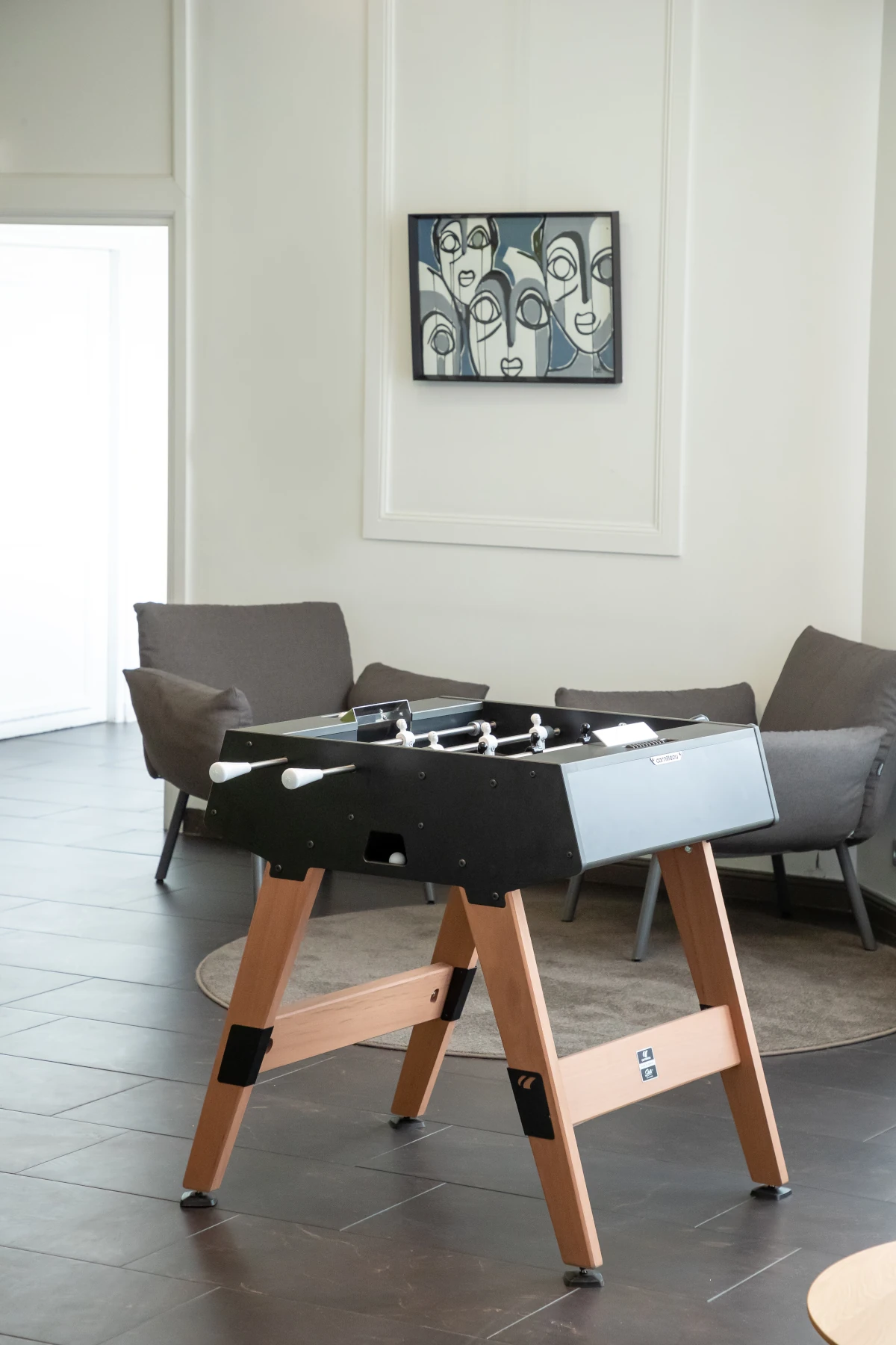 Baby-foot Cornilleau noir avec pieds en bois dans un salon contemporain