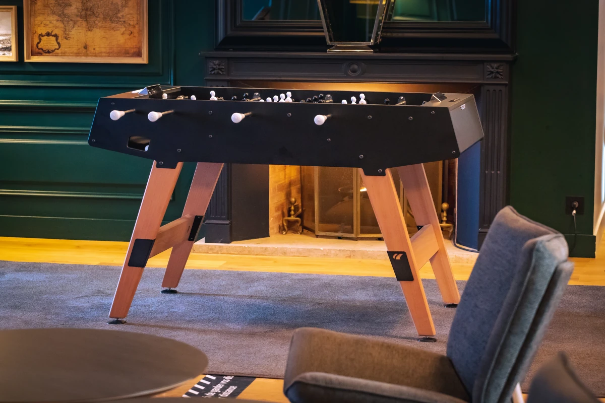 Baby-foot Cornilleau noir installé devant une cheminée dans un intérieur élégant