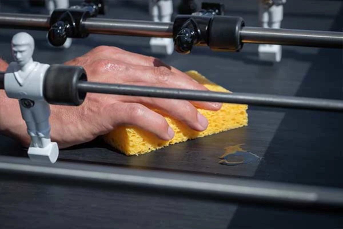 Nettoyage de la surface de jeu d’un baby-foot Cornilleau avec une éponge